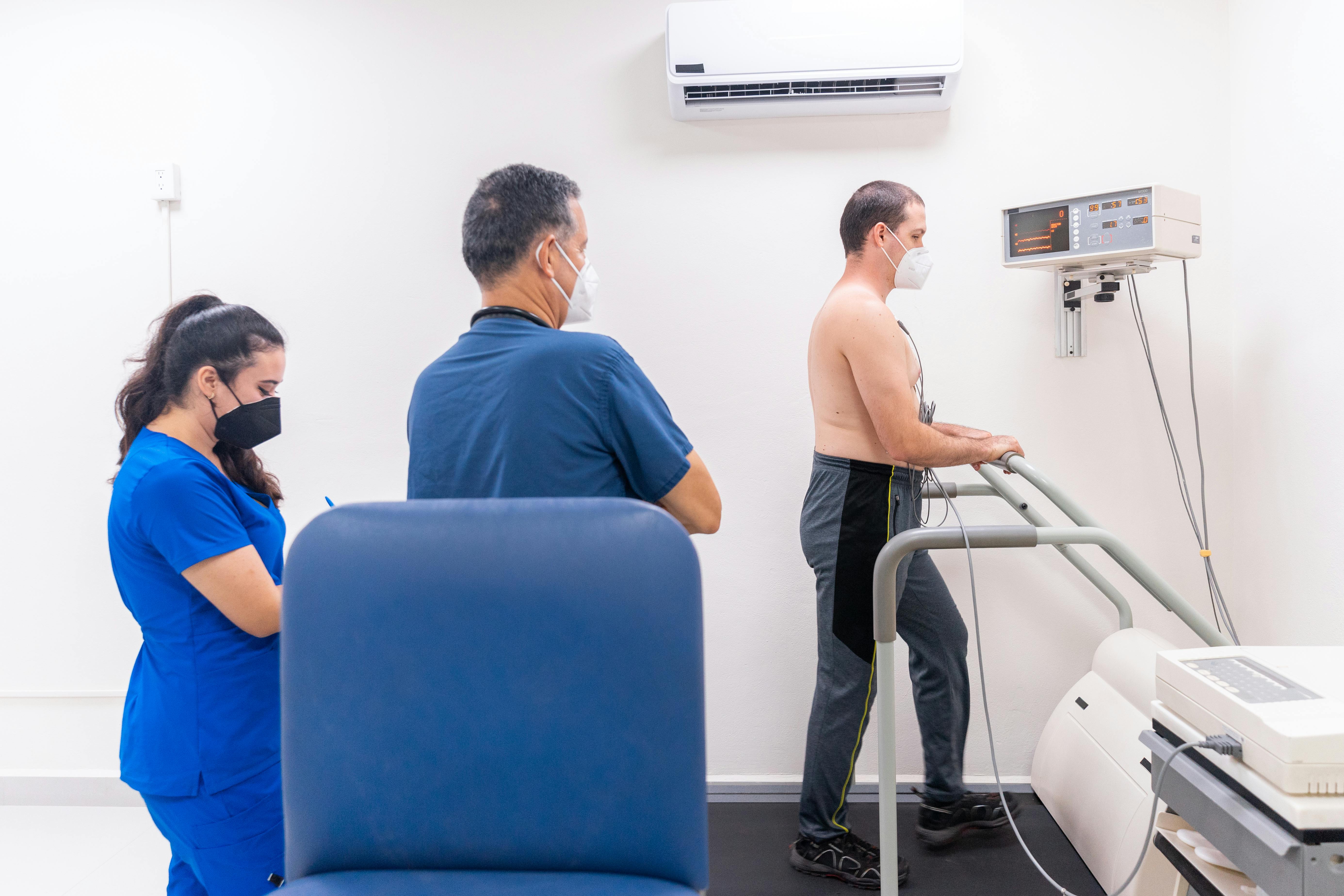 Healthcare providers observe a man on a treadmill performing a heart test