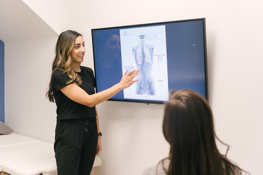 Physiotherapist reviews an Xray image on a screen with a patient.